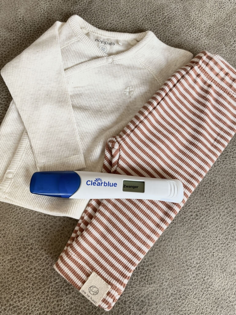 Afbeelding zwangerschapstest en babykleding Afbeelding zwangerschapstest en babykleding